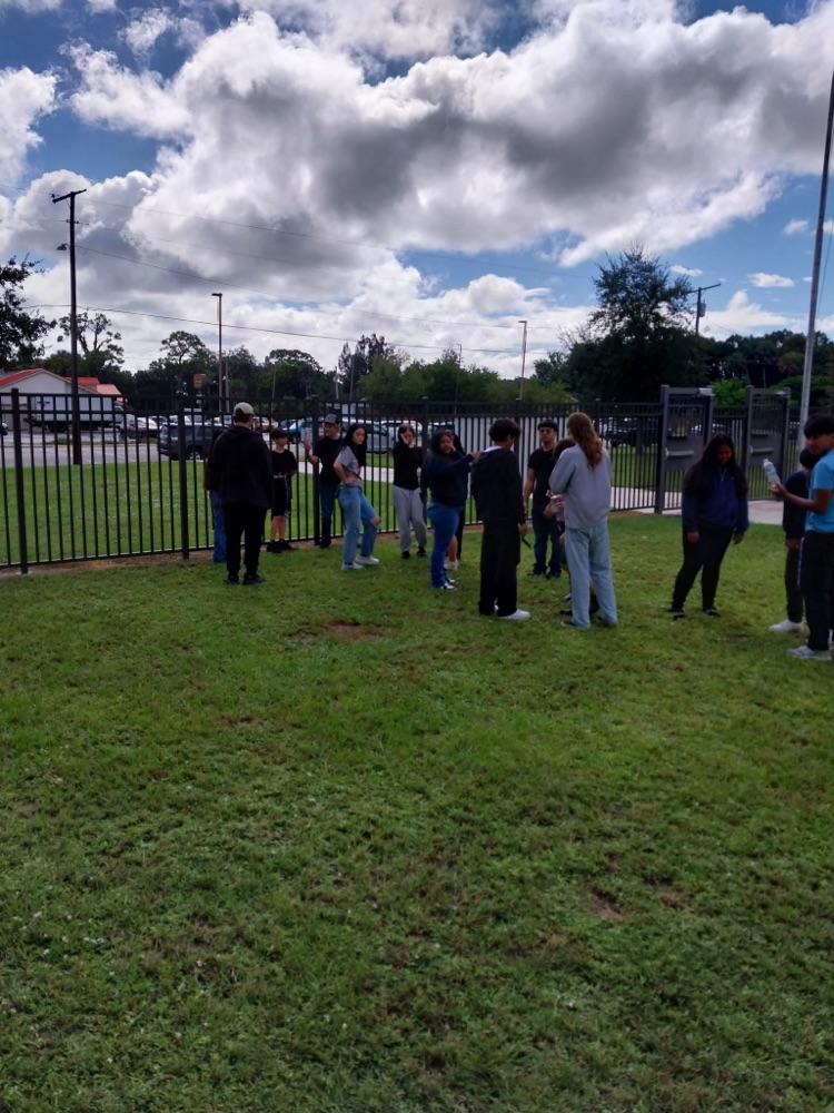 students doing science project by flagpole 