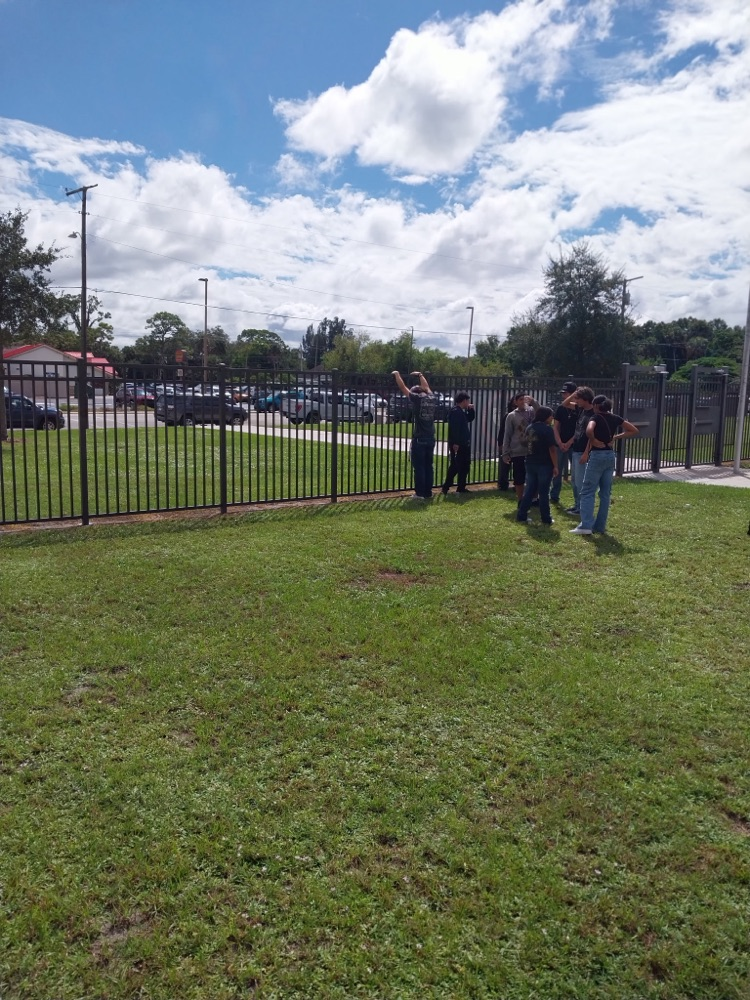 students doing science project by flagpole 