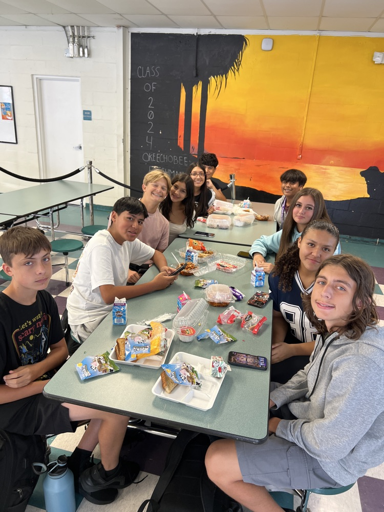 ten students sitting in cafeteria eating their lunch
