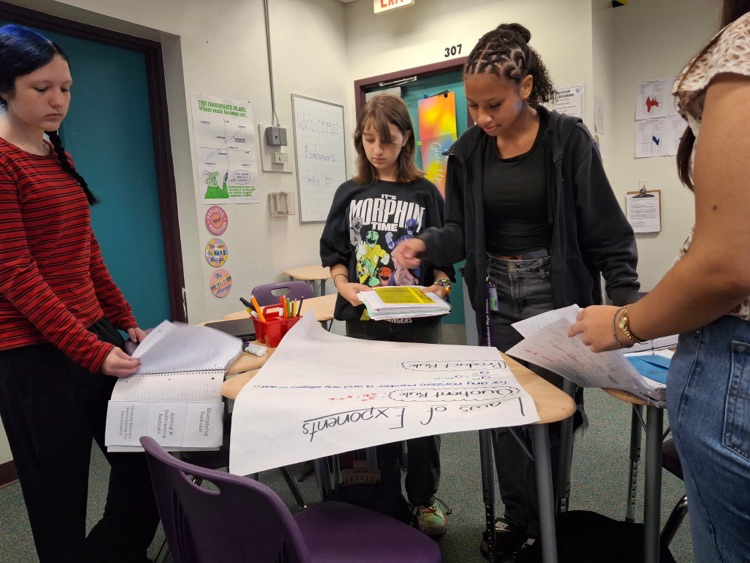 four students working on algebra posters