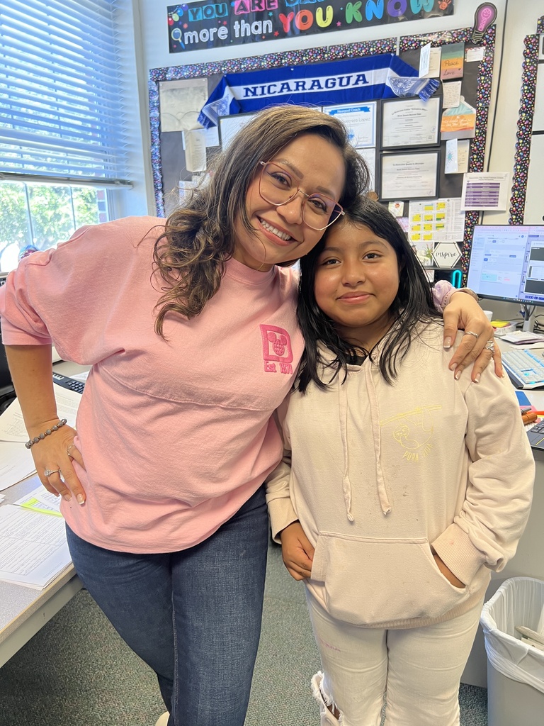 teacher and student hugging in class wearing pink