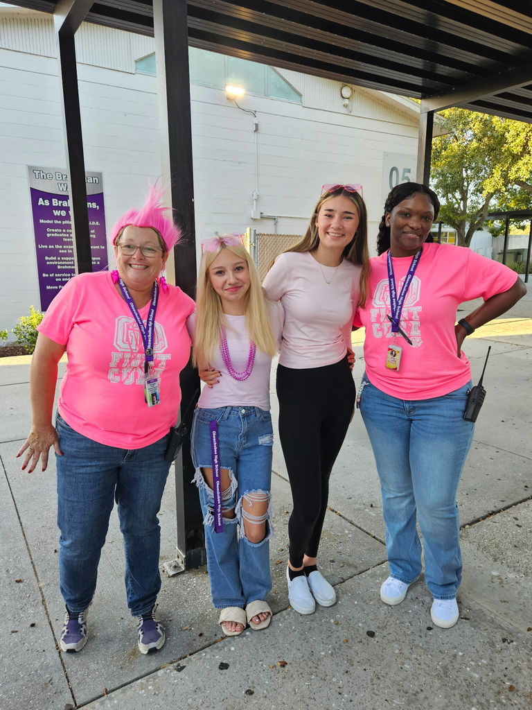 two school members with two students wearing pink outside