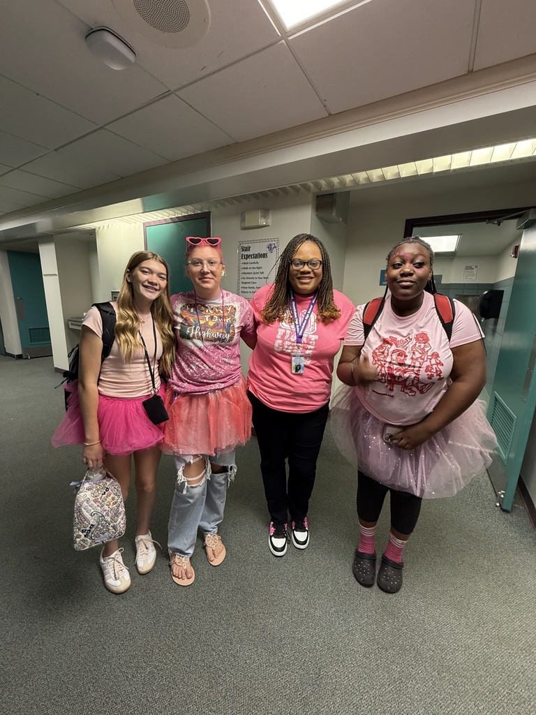 two students standing with two staff members in school hallway