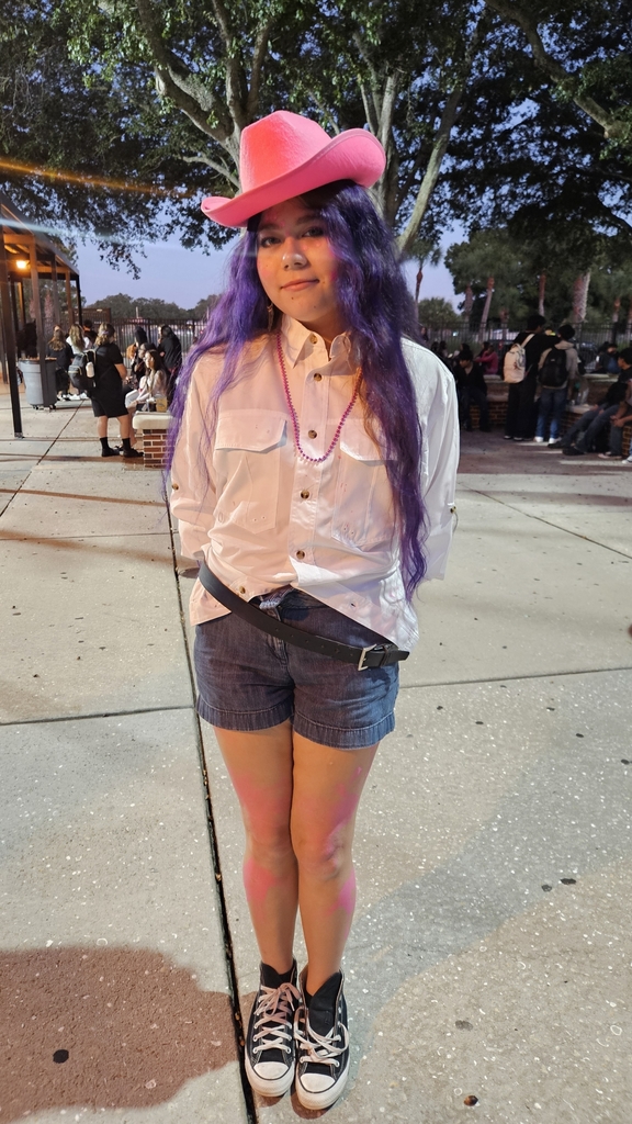 student outside in school courtyard wearing pink cowboy hat