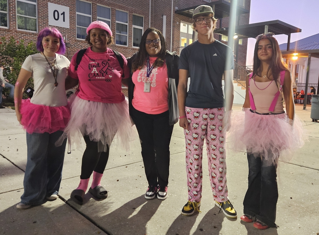 four students standing with assistant principal outside in school courtyard