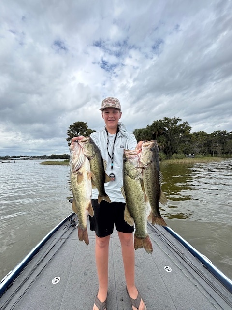 student holding fish standing on a boat