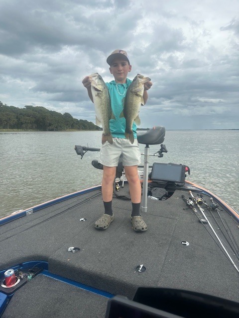 student holding fish standing on a boat