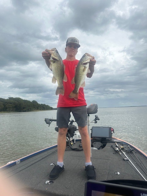 student holding two fish on a boat