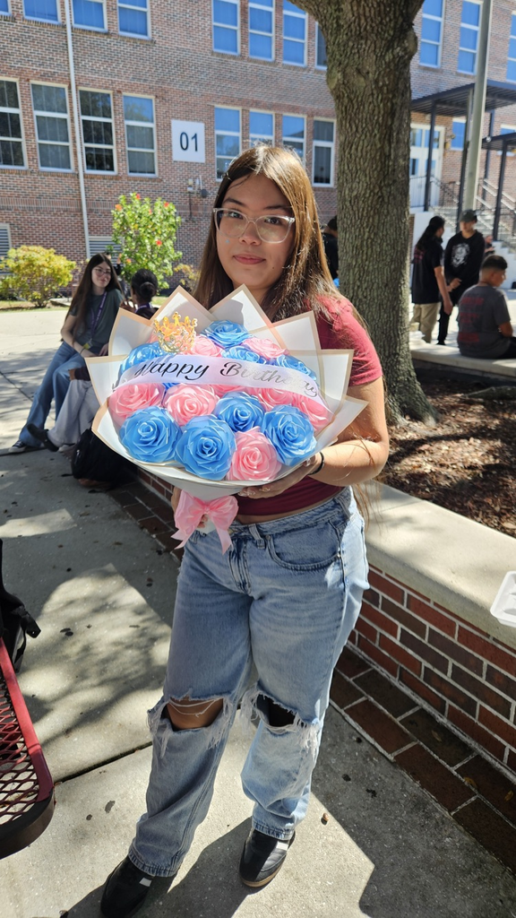 girl holding bouquet of flowers at school courtyard