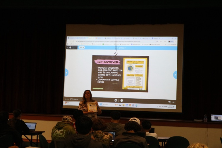 teacher speaking to auditorium about club