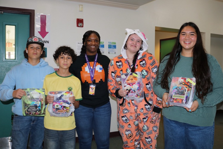 four students and a teacher showing off attendance prizes