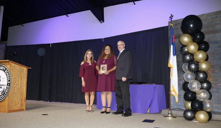 assistant principal with superintendent and school board member on stage