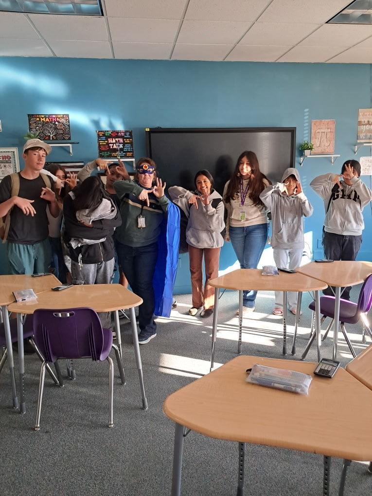 classroom with students signing 6-7 and teacher dressed as superhero