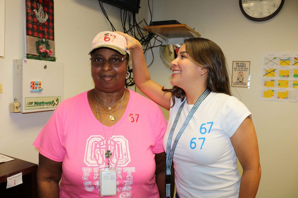 two staff members showing off their 6-7 for 67th day at school