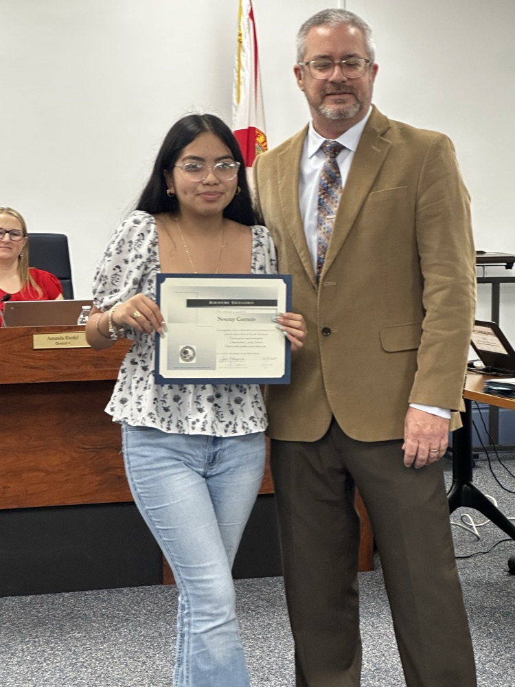 student posing with certificate next to superintendent