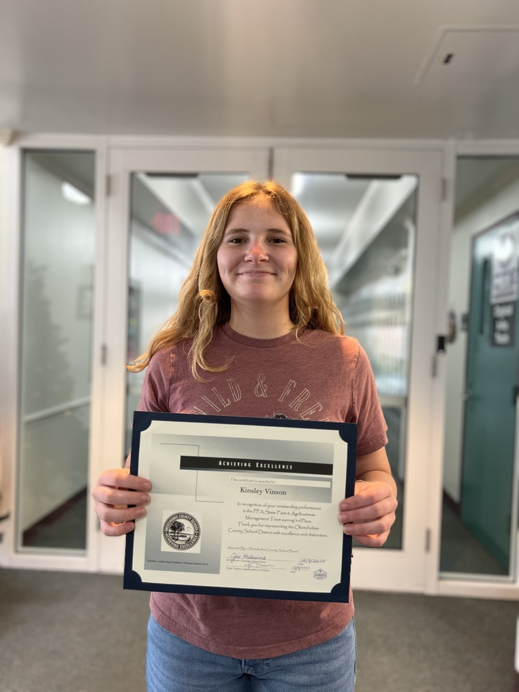 student holding certificate in school hallway