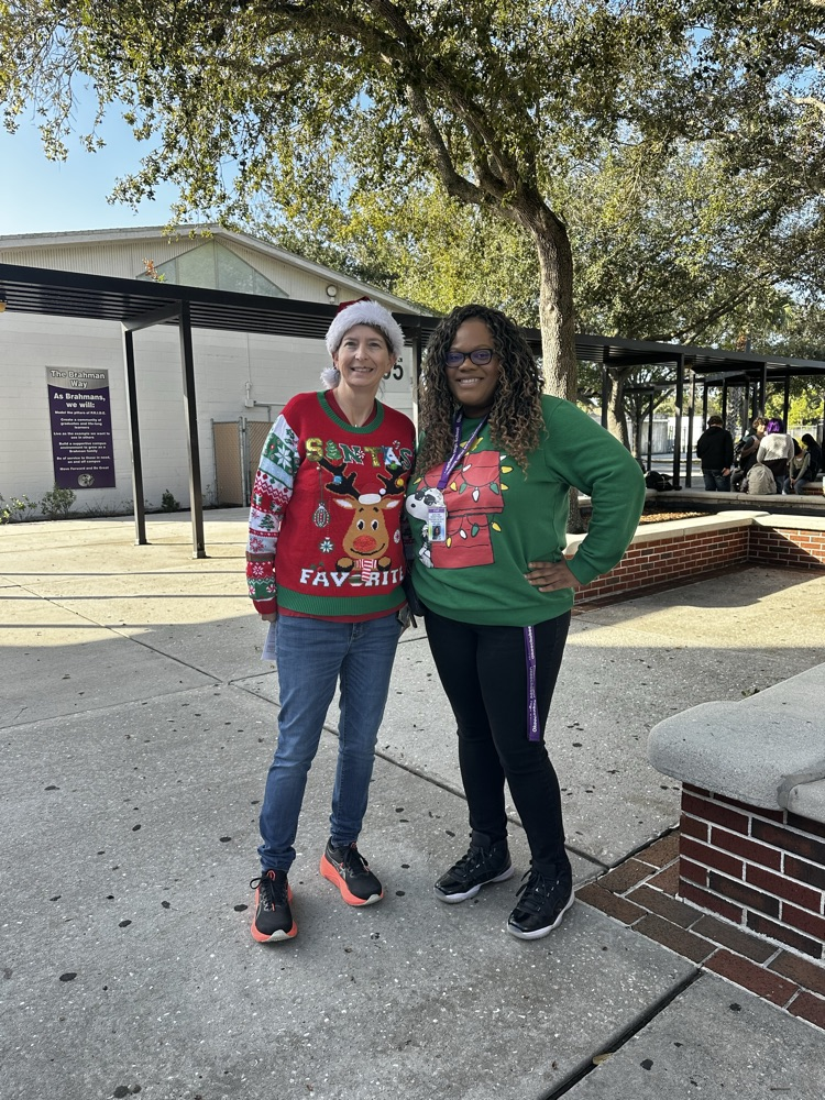 two staff members wearing ugly sweaters in school courtyard 
