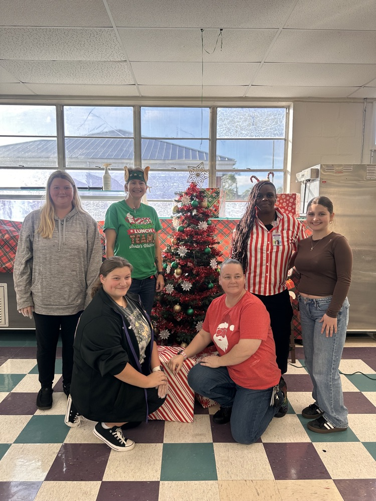 cafeteria staff and three students by Christmas tree