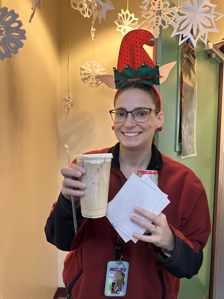 teacher holding breakfast treats by classroom door