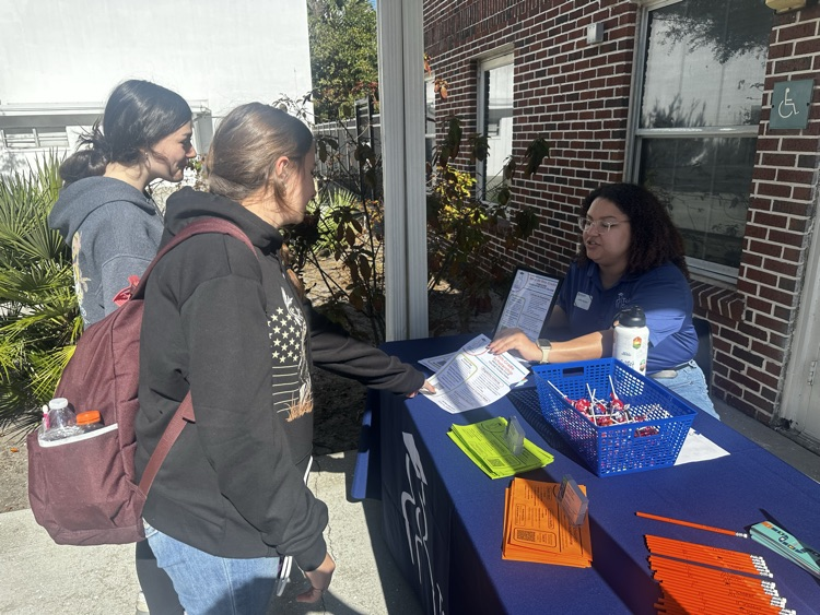 two students talking to adult in booth