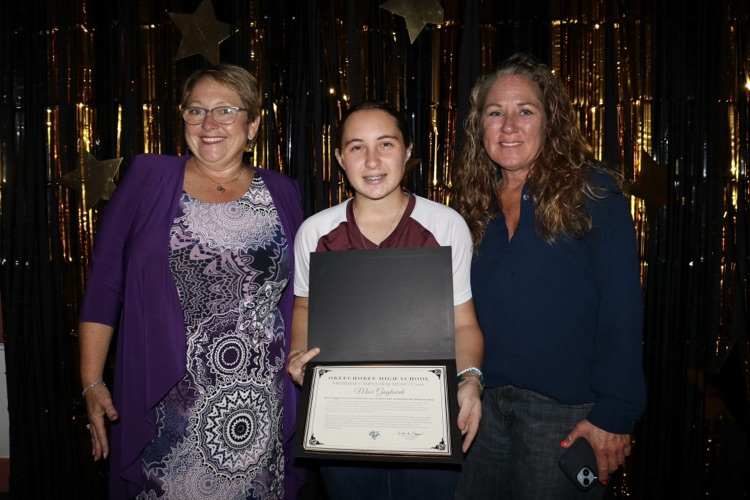 student with principal and mom at banquet