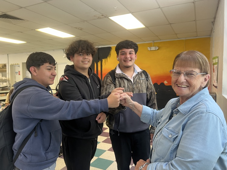 three students with a staff member fist bumping