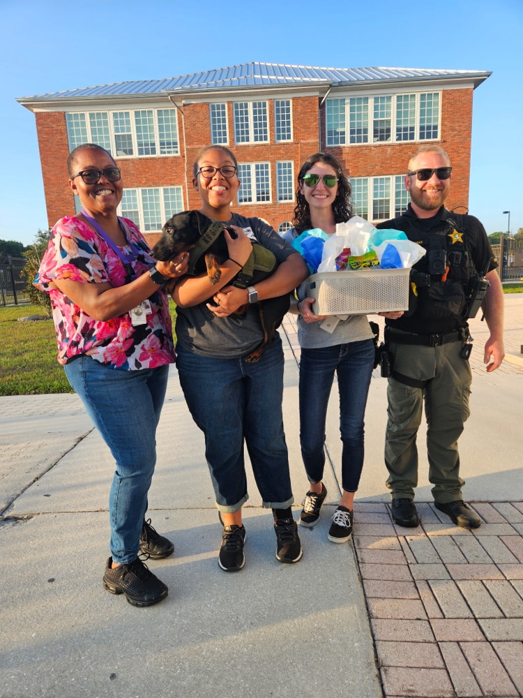 three adults and one senior student receiving a gift basket
