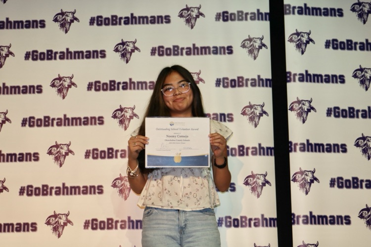 student holding certificate on stage