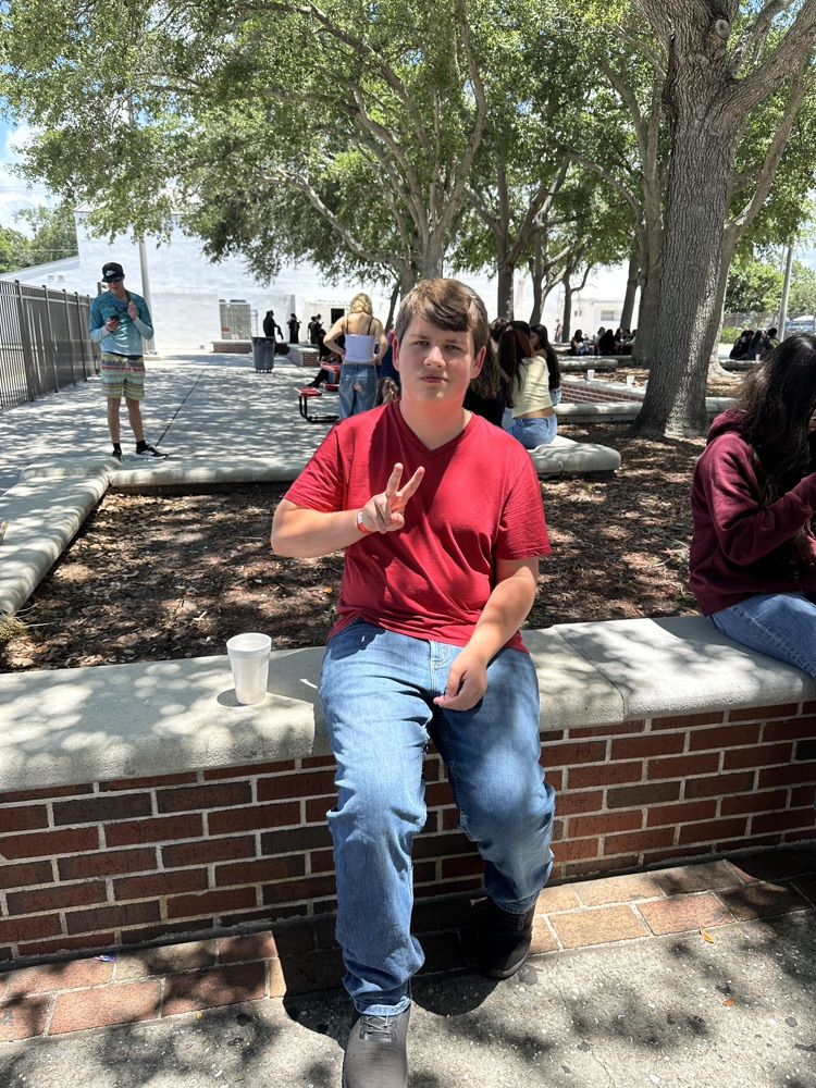 one student in courtyard giving peace sign