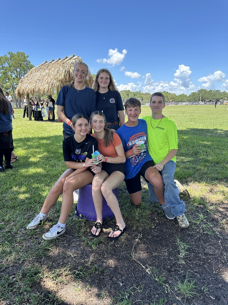 group of students sitting in field eating Kona ice