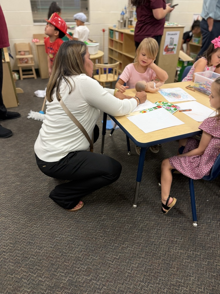 teacher bent down helping students