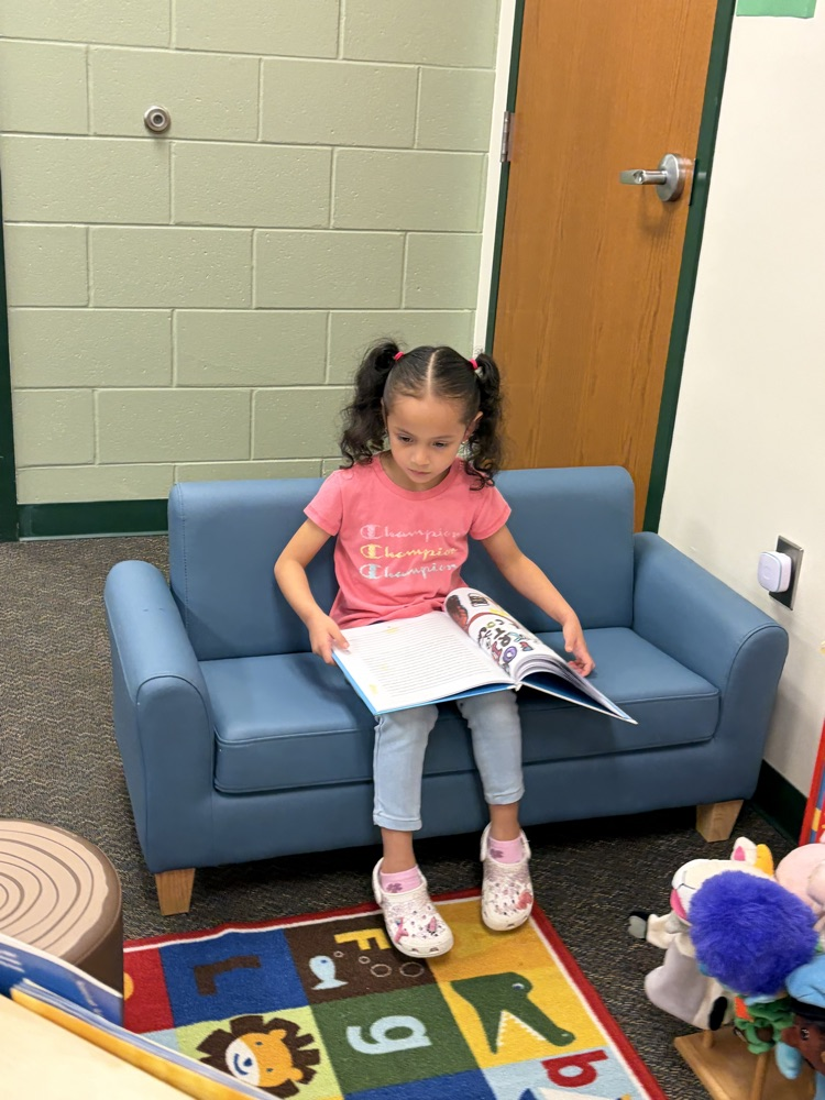 student reading a book in vpk