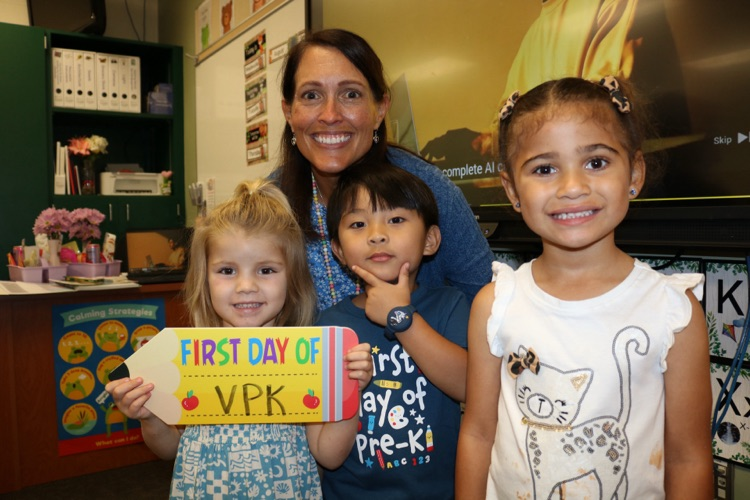 teacher and three students with first day of VPK sign