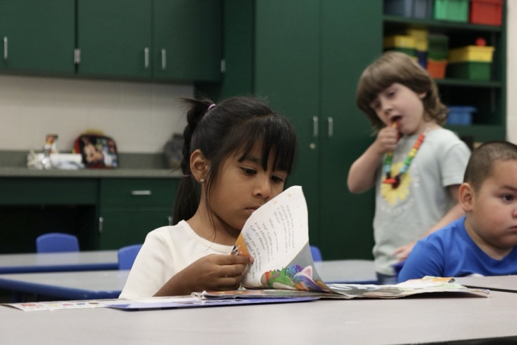 student in vpk desk reading