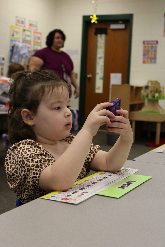 VPK student staring intently at toy while sitting on desk
