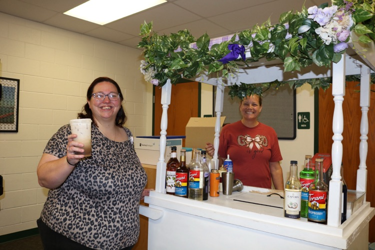 staff member holding coffee next to cart