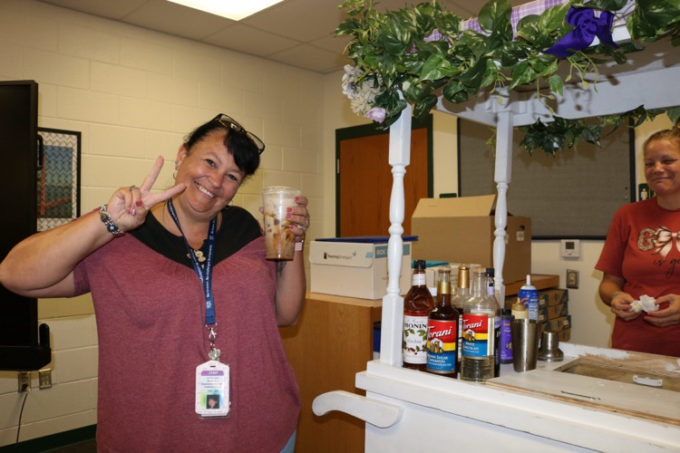 staff member holding coffee next to cart