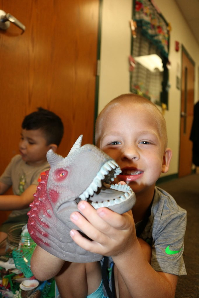 student playing with dinosaur head
