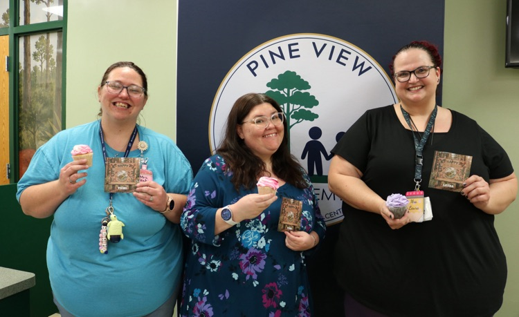 three staff members celebrating birthdays with cupcakes