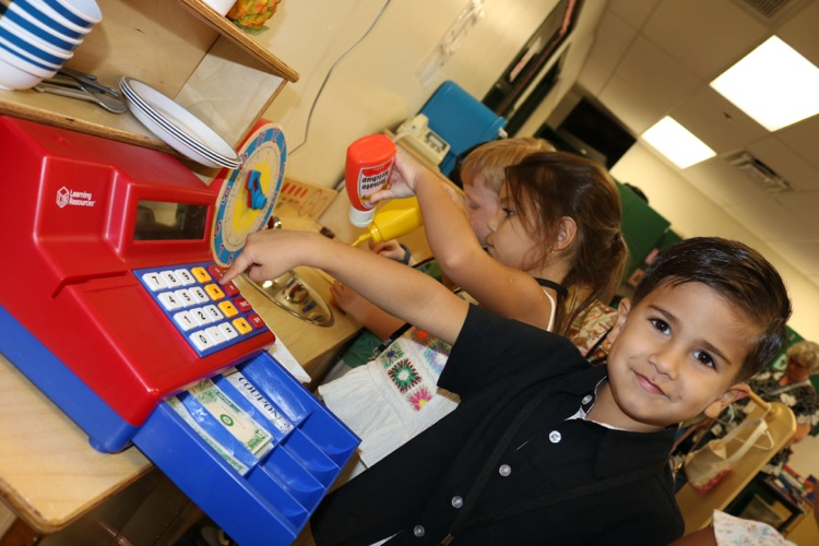 student playing with cashier register in class