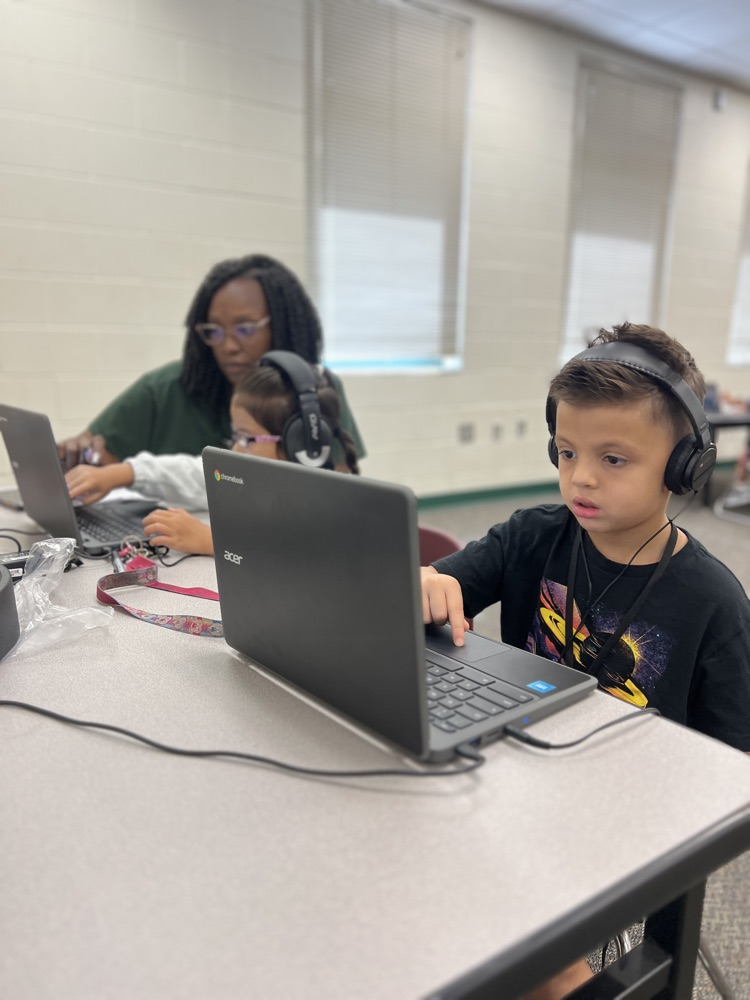 students testing on computer with a teacher