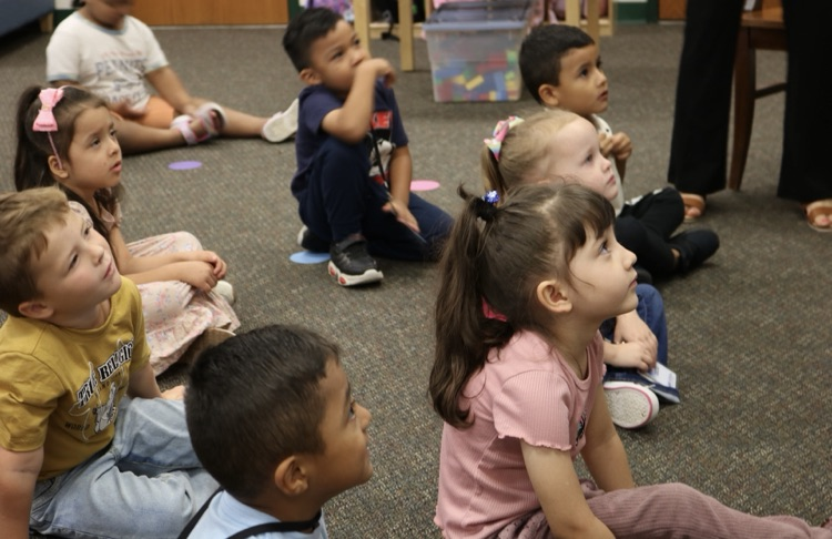 students looking at teaching while sitting in carpet 