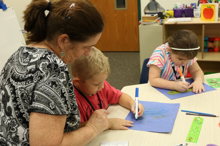 student and teacher writing on paper