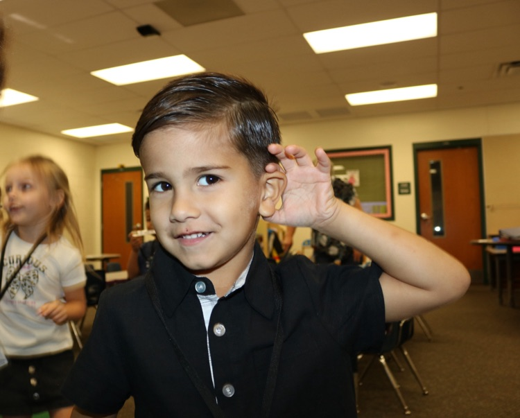 student with hand covering his ear 