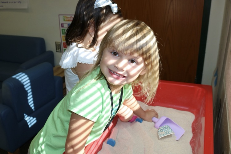 girl playing in toy sand box 