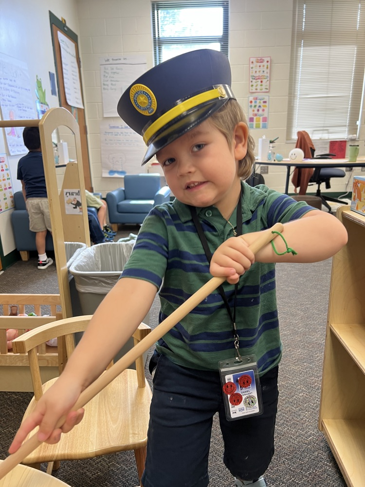 student wearing blue and green sweeping in class