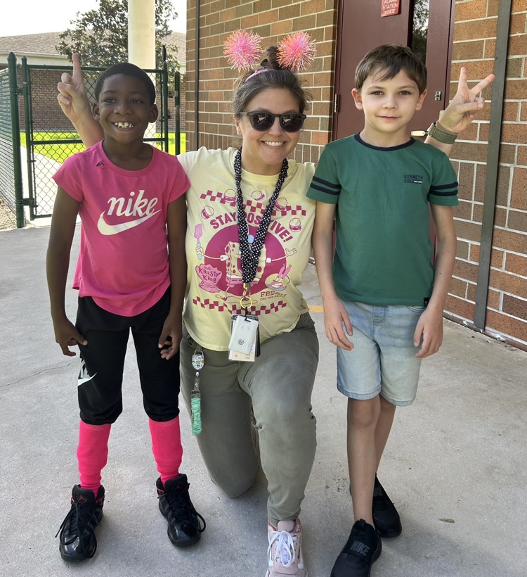 Two children and an adult woman are posing for a photo outside a brick building.