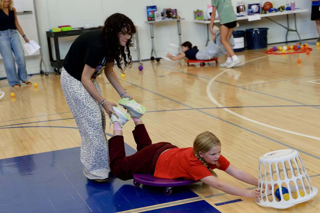 Students participate in a team game using scooters, baskets, and colorful balls during the OSMS Celebration of Learning.