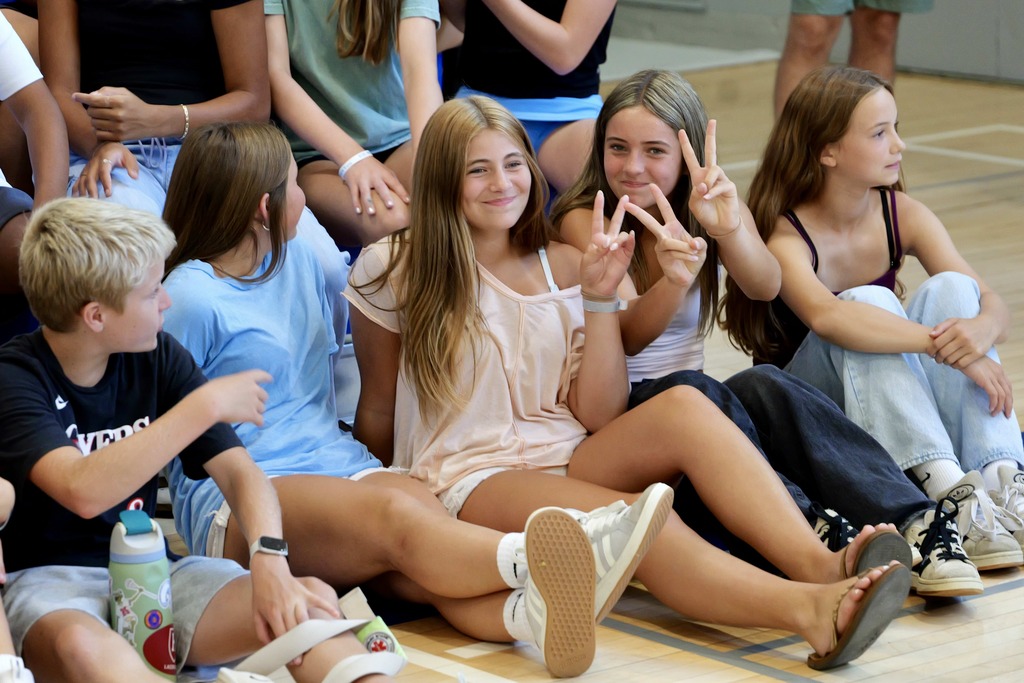 Suggested alt text: OSMS students sit together during the whole-school Celebration of Learning, with two students smiling toward the camera.