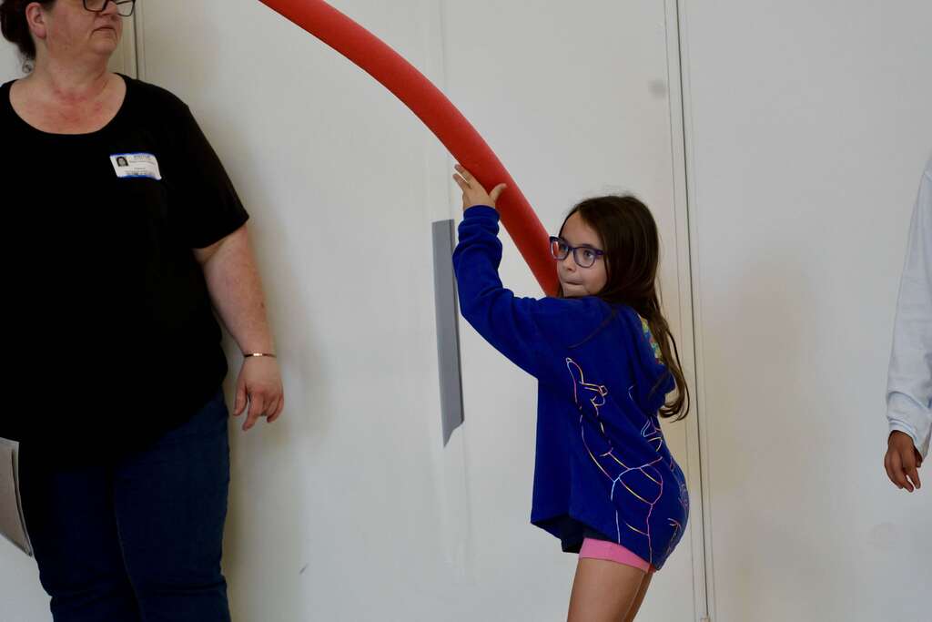 A student participates in a school activity during the OSMS Celebration of Learning while an adult staff member stands nearby.
